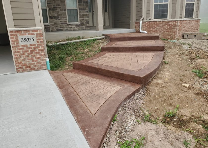 Home Page Image 1 Decorative stamped concrete walkway leading to a residential entrance, featuring intricate patterns and a rich brown color, showcasing Morici Bros Concrete's craftsmanship in Milwaukee area concrete services.