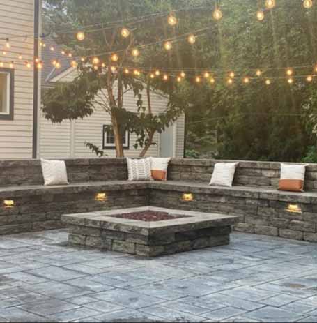 Custom concrete patio with built-in seating, fire pit, and decorative lighting, designed for outdoor gatherings and relaxation.