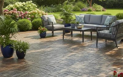 Beautifully stamped concrete patio with outdoor seating area, decorative plants, and lush landscaping, enhancing outdoor aesthetics for home improvement.
