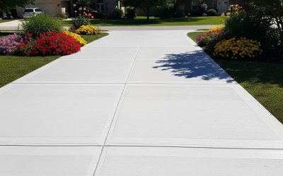 Freshly resurfaced concrete driveway with smooth texture, surrounded by vibrant flower beds, showcasing aesthetic appeal and quality craftsmanship.